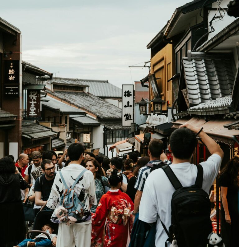 Crowded street scene in Kyoto with traditional architecture and people in kimonos.