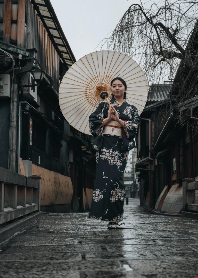 Japanese woman in a kimono with umbrella in Kyoto's historic district on a rainy day.