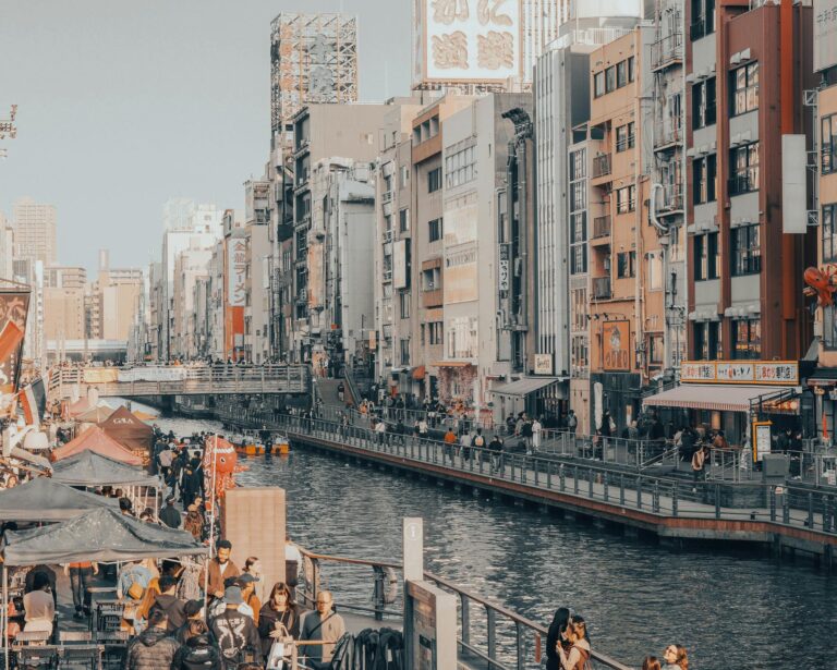 Vibrant cityscape of Kyoto's canal area with pedestrians and colorful buildings showcasing urban life.
